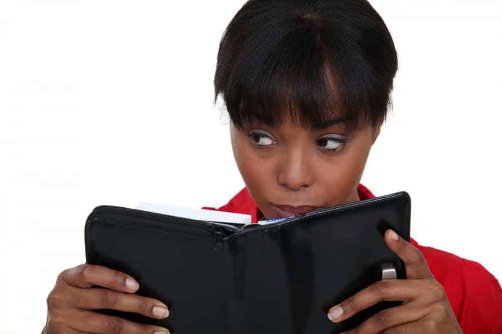 Image of a young black woman reading a planner page looking annoyed