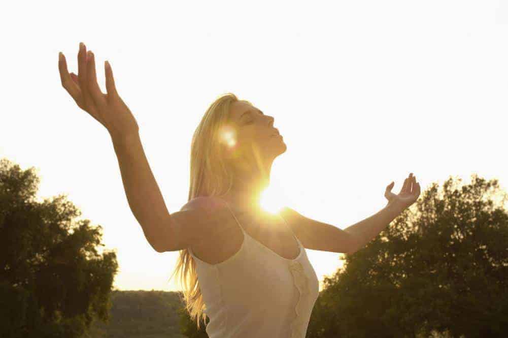 Image of young woman with her arms to the sky in prayer, being spiritual.